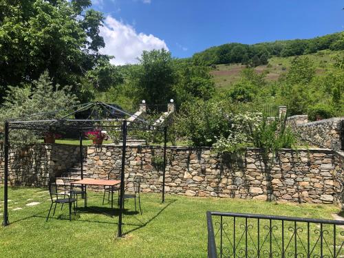 a table and chairs in a garden with a stone wall at Guesthouse Kontogianni - Materka in Nymfaio