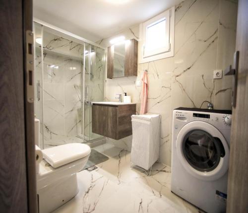 a bathroom with a washing machine and a washer at Cozy Like Home in Maniákoi