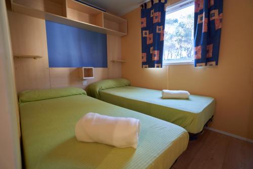 two beds in a small room with a window at ZALUAY - Mobile Homes in Isla Cristina