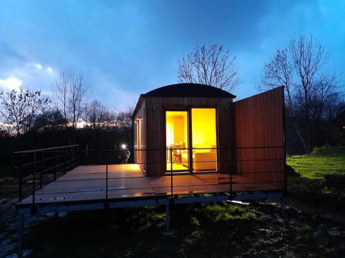 a small cabin with a deck in a field at Au p'tit pré des salers in Hamois