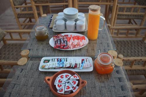a wooden table with plates of food and orange juice at SurfAppart Morocco in Tamraght Ouzdar