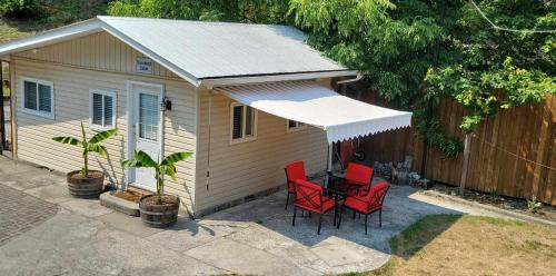 a small house with red chairs and an awning at Riverbend Guest House in Chilliwack