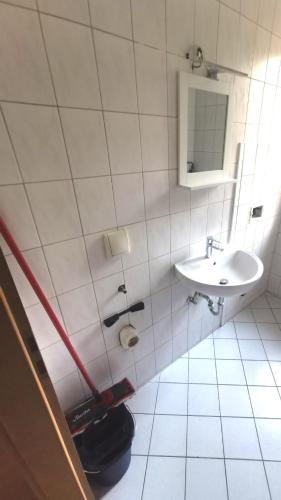 a white tiled bathroom with a sink and a toilet at Monteurzimmer am Bahnhof Biesenthal - 3 große Apartments in Biesenthal