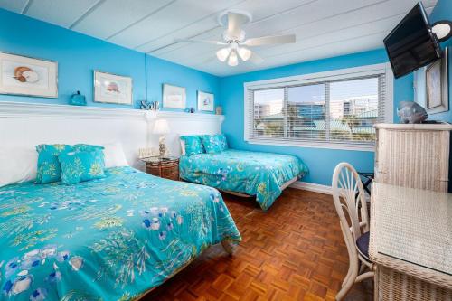 ein blaues Schlafzimmer mit 2 Betten und einem Fenster in der Unterkunft Seaspray Condos 106D in Fort Walton Beach