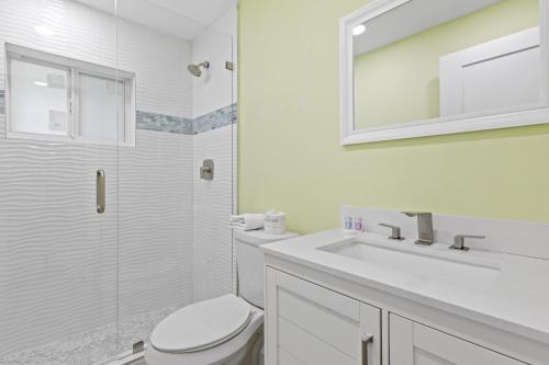 a white bathroom with a toilet and a sink at Pirates Cove Cottage at Palm View Inn of Sanibel with Bikes in Sanibel