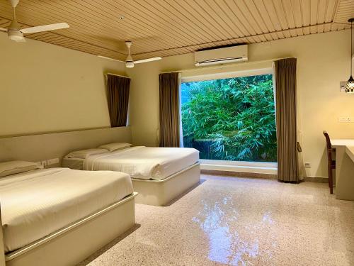 MandapamJoe's Beach Shack - Beach resort, Ramanathapuram的一间有两张床和一扇大窗户的卧室