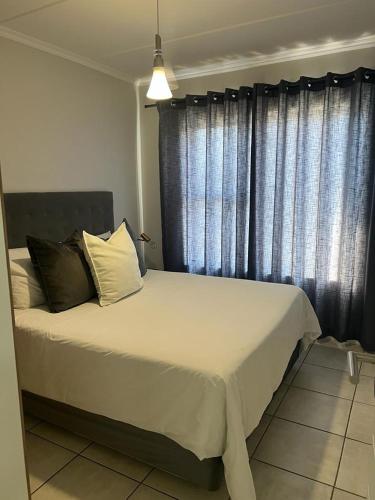 um quarto com uma cama branca e uma janela em Greenpark Apartment em Kempton Park