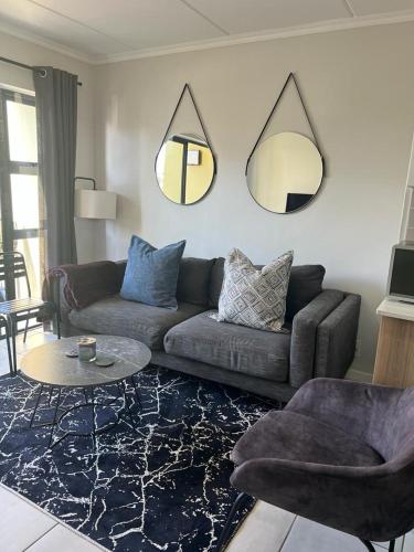 a living room with a couch and two mirrors on the wall at Greenpark Apartment in Kempton Park