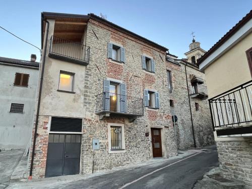 an old brick building with a balcony on a street at La Casa di Margot - Alloggio Blu in Murazzano