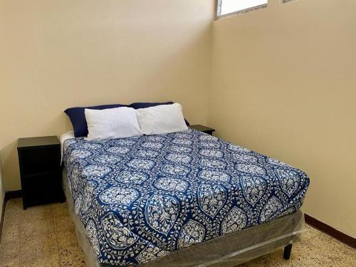 Schlafzimmer mit einem Bett mit einer blauen und weißen Bettdecke in der Unterkunft Casa Quetzal in Guatemala