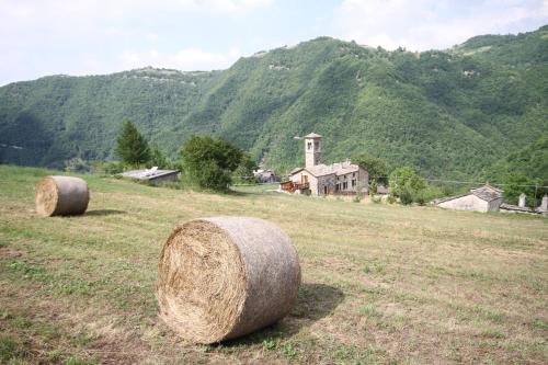 two large hay bales in a field with a house at Agriturismo Cà Sonino in Bettola