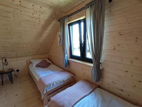 two beds in a log cabin with a window at Przystanek Śnieżka in Kowary