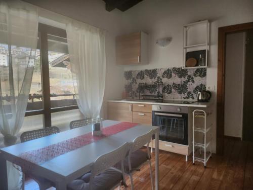 uma cozinha com uma mesa e cadeiras, uma mesa e uma janela em Margiolà em Calalzo