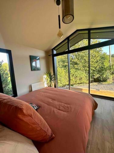 un grand lit dans une chambre avec une grande fenêtre dans l'établissement Maison de charme pleine nature pour couple, à Liessies