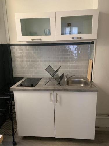 une cuisine avec des armoires blanches et un évier dans l'établissement Très joli appartement à Puteaux centre ville, à Puteaux
