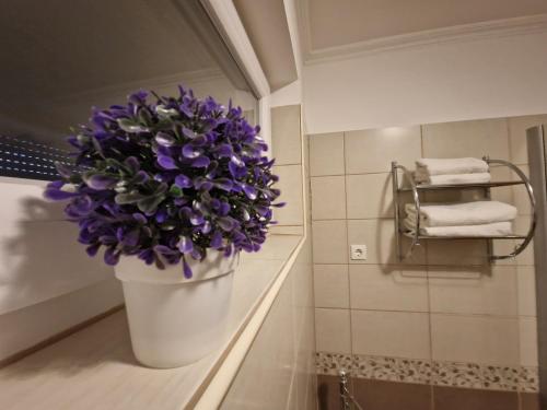 a large white bucket with purple flowers in a bathroom at Centrum Business Apartman Szekszárd in Szekszárd