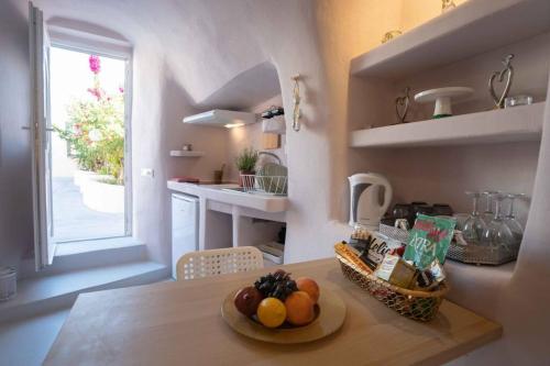 a kitchen with a table with a bowl of fruit on it at Bird Nest-Santorini Cave houses in Fira