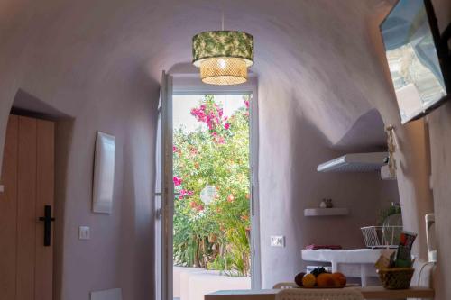 a kitchen with a door leading to a garden with pink flowers at Bird Nest-Santorini Cave houses in Fira