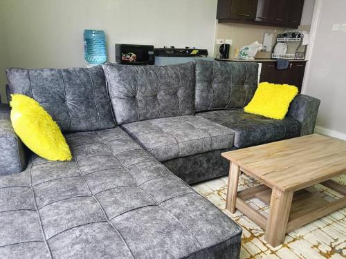 a gray couch with yellow pillows and a coffee table at Legatus Cozy Homes in Ongata Rongai 