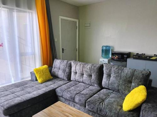 a gray couch with yellow pillows in a living room at Legatus Cozy Homes in Ongata Rongai 