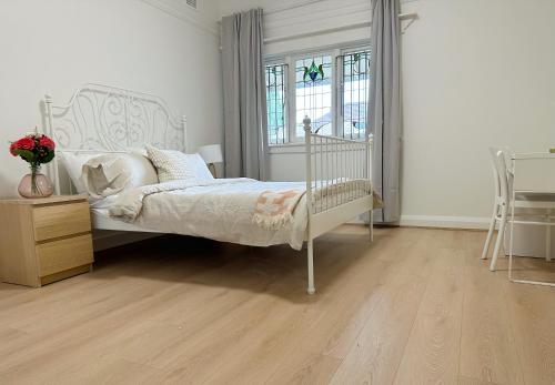 a bedroom with a white bed and a wooden floor at three bedroom house within walking distance to light rail station in Sydney