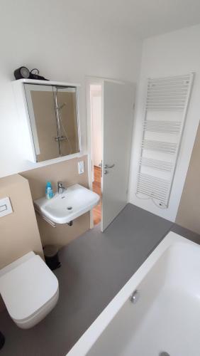 a white bathroom with a toilet and a sink at FeWo "Leuchtturmliebe" in Kassow