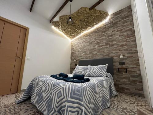 1 dormitorio con cama y pared de ladrillo en Casa entre Rocas Setenil, en Setenil