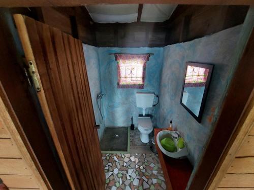 a small blue bathroom with a toilet and a window at GENTE D'AQUI Ngê D'ai êê in São Tomé