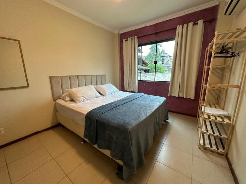 Schlafzimmer mit einem Bett und einem Fenster in der Unterkunft Apto acomchegante próximo a Praia do Bosque - 3 quartos - Ar condicionado - Garagem - TV Smart in Rio das Ostras