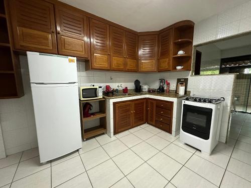 eine Küche mit einem weißen Kühlschrank und Holzschränken in der Unterkunft Apto acomchegante próximo a Praia do Bosque - 3 quartos - Ar condicionado - Garagem - TV Smart in Rio das Ostras