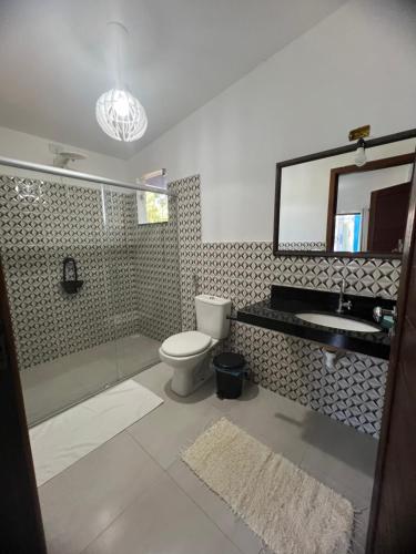 a bathroom with a toilet and a sink and a mirror at Residência Vittoria - Apartamento aconchegante em condomínio no centro de Arraial d Ajuda in Porto Seguro