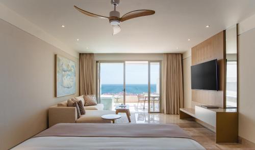 a bedroom with a bed and a couch and a television at Grand Velas Boutique Hotel in San José del Cabo