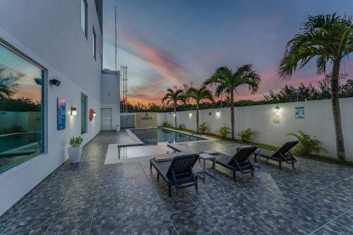 a patio with chairs and a table and a pool at La Venta Inn Ciudad del Carmen in Ciudad del Carmen