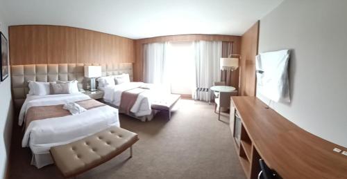 a hotel room with two beds and a television at White Plaza Hotel in Curitiba