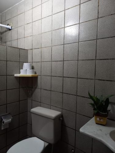 a white tiled bathroom with a toilet and a sink at Pousada Formosa in Porto Seguro