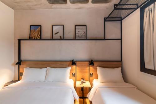 2 camas en una habitación con paredes blancas en ibis Tubarão, en Tubarão