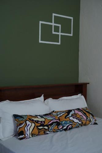 a bed with white pillows and a green wall at The Last Try - Secret Ashram Coorg in Siddapur