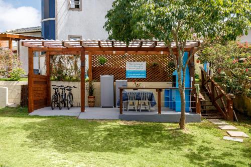 a pergola with a table and chairs in a yard at Paradise Bangalô in Florianópolis