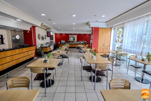 a restaurant with tables and chairs in a room at Sables Hotel Guarulhos in Guarulhos
