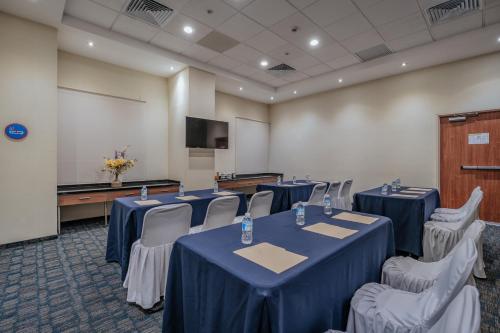 a conference room with blue tables and chairs and a screen at La Venta Inn Ciudad del Carmen in Ciudad del Carmen