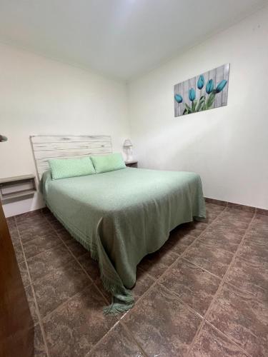 a bedroom with a bed with a green bedspread at CABAÑAS MECHI in Mar del Plata