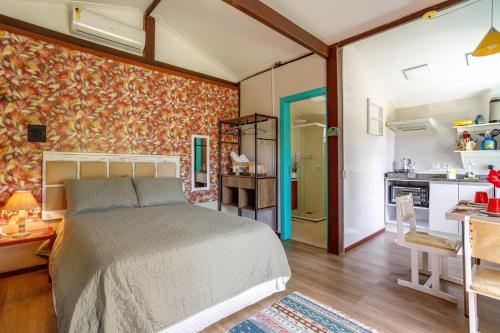 a bedroom with a bed and a kitchen at Paradise Bangalô in Florianópolis