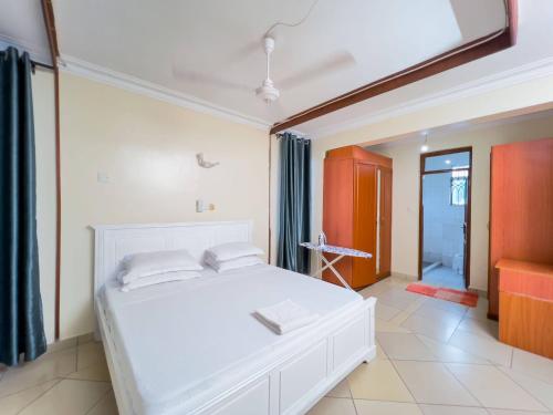 a bedroom with a white bed and a bathroom at Majestic Homes in Nyali