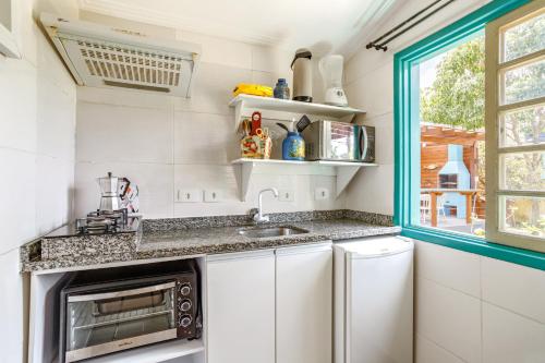 a kitchen with a sink and a microwave at Paradise Bangalô in Florianópolis