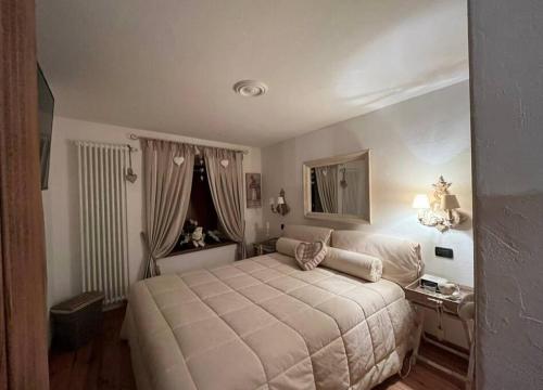 een slaapkamer met een groot bed en een spiegel bij La casetta del cuore tra terme e montagna in Pré-Saint-Didier