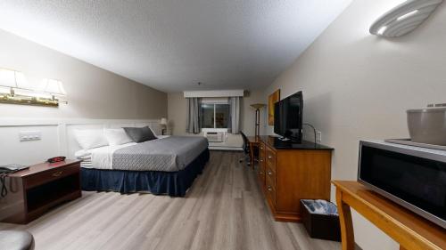 a hotel room with a bed and a flat screen tv at Presque Isle Hotel in Presque Isle