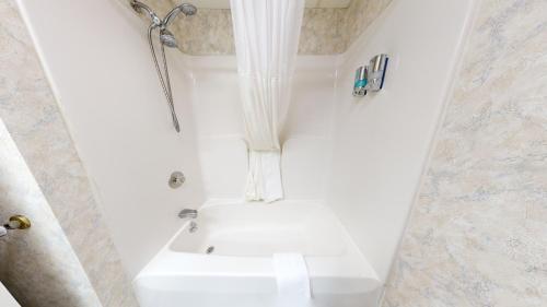 y baño blanco con ducha y aseo. en Presque Isle Hotel, en Presque Isle