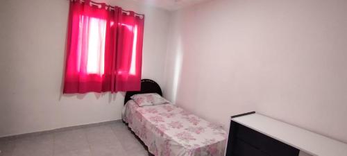 een kamer met een bed en een rood raam bij QUARTO COM BANHEIRO PARA ALUGAR POR DIÁRIA in Garanhuns