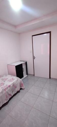 een witte kamer met een bed en een deur bij QUARTO COM BANHEIRO PARA ALUGAR POR DIÁRIA in Garanhuns