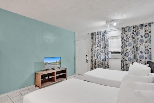 um quarto de hotel com duas camas e uma televisão em Walk to Hallandale Beach Pool Christmas Retreat em Hallandale Beach